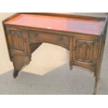 An oak effect desk, two cupboards with central drawer above, gothic decoration, shaped plank legs,