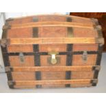 An antique dome top traveling trunk clad in leather and metal work straps, twin leather handles