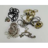 A white metal charm bracelet together with a dress necklace, brooches and other items.
