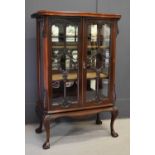 A late 19th century mahogany glazed display cabinet, the serpentine top above two astragal glazed