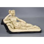 A resin figure of a classical lady laid upon an ebony bed, 21cm high by 33cm.