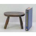 An antique oak stool carved Rutland to the top, 22cm by 15cm together with a book on