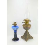A late 19th century oil lamp with cranberry glass shade together with a blue twist glass lamp.