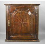 A late 18th century and later oak spice cupboard, inlaid with marquetry starburst, and the fielded