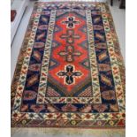 A Middle Eastern wool rug, with four stylised crosses to the red ground central panel, bordered by