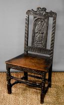 A late 18th/early 19th century hall chair, the back panel carved with a saint.