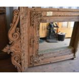 A large wooden window frame, made into a mirror, with a twin scroll pediment, 116cms tall by