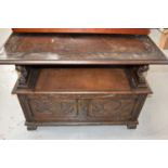 An oak monks bench/ box settle with carved decoration to the front and top and having lion form