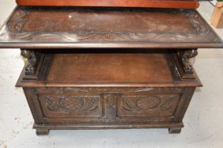 An oak monks bench/ box settle with carved decoration to the front and top and having lion form
