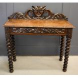 An oak 1930s silver table, the carved back depicting a face mask and scrollwork, with a frieze