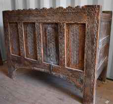 A 19th century carved chest, the planked top above a four panel front, carved with decoration and