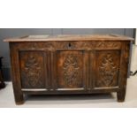 An 18th century oak coffer, with triple panelled lid and front, carved with diamonds, raised on