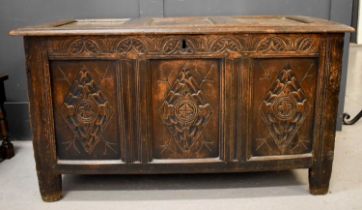 An 18th century oak coffer, with triple panelled lid and front, carved with diamonds, raised on