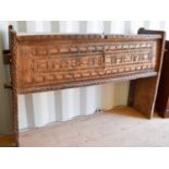 A boarded wooden chest, raised on tall end boards, the top and front carved with decoration, 95cms