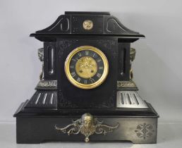 An antique slate mantle clock, with visible escapement, twin hoop and female face mask handles,