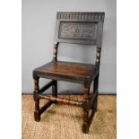 An 18th century oak chair, the back panel carved with nulled top rail, raised on turned legs and