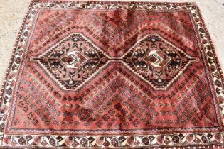 A Persian wool rug with red / brown ground, hand woven in soft pile, the centre with decorative