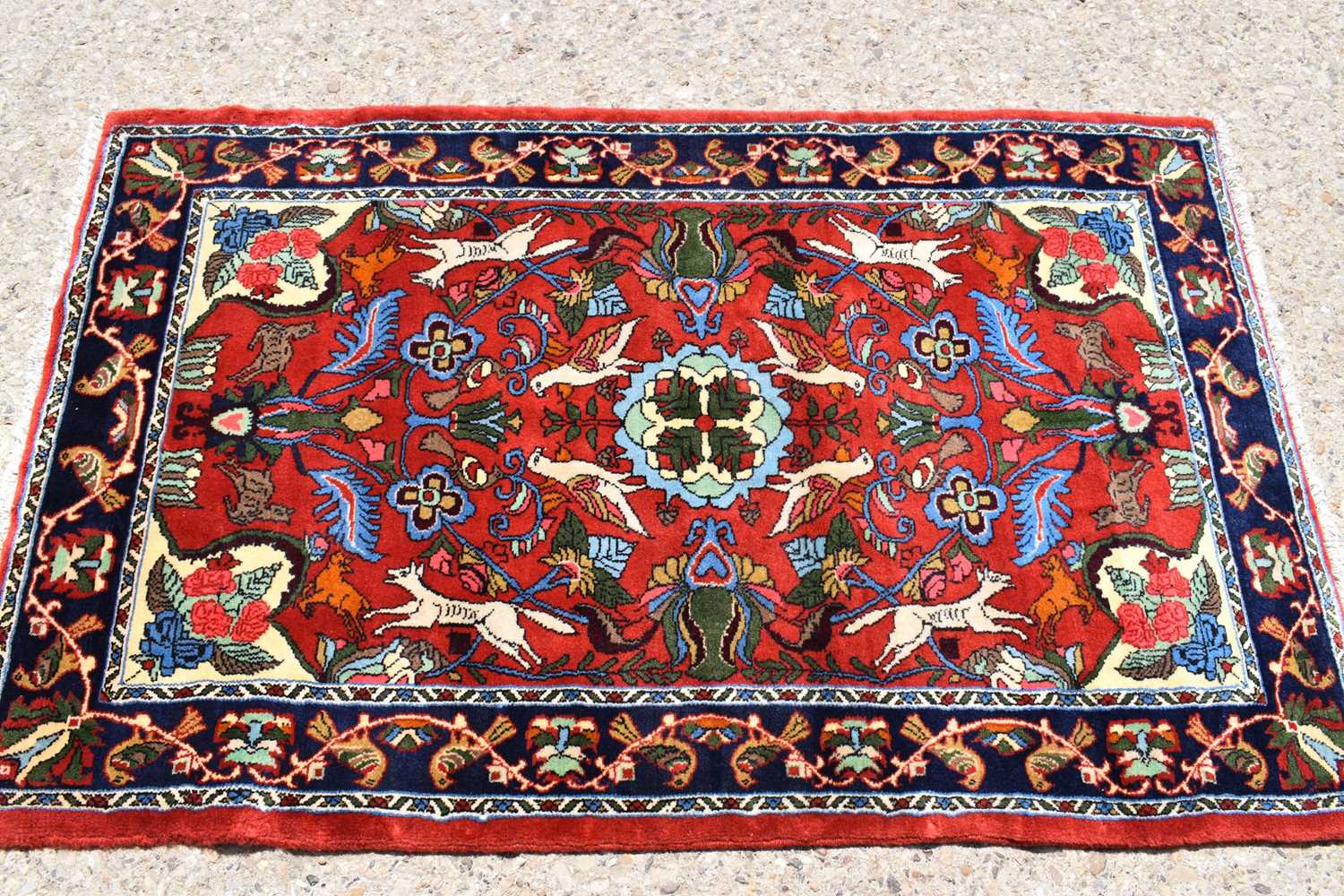 A fine Middle Eastern wool rug, hand woven in deep pile, the red ground centre depicting birds,