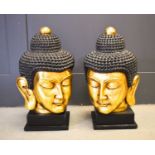 A pair of 20th century Buddha heads, with gilded faces, raised on square plinths, 56cm high.