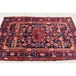 A Middle Eastern red ground wool rug, the centre depicting stylized figures and architecture