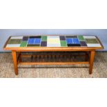 A retro tiled top table, circa 1968, the coloured tiles set in a teak frame with magazine