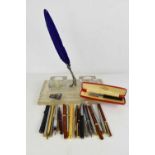 A 1950s pressed glass inkstand, a quil and stand, and a group of pens and propelling pencils, to