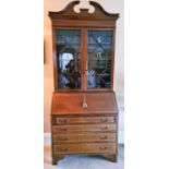 A mahogany bureau bookcase, the top with glazed astrigal doors, split pediment top, the bureau