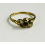 A 9ct gold, dark stone, possibly jet, and diamond illusion set three stone ring, central stone