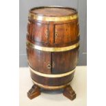 A 19th century oak coopered barrel drinks cabinet bound in brass and having four integral doors,