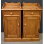 A pair of pine bedside cabinets, with single drawers and corresponding cupboard doors, 77 by 38 by