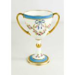A Minton porcelain twin handled christening cup, decorated with floral garlands, blue bow and gilded