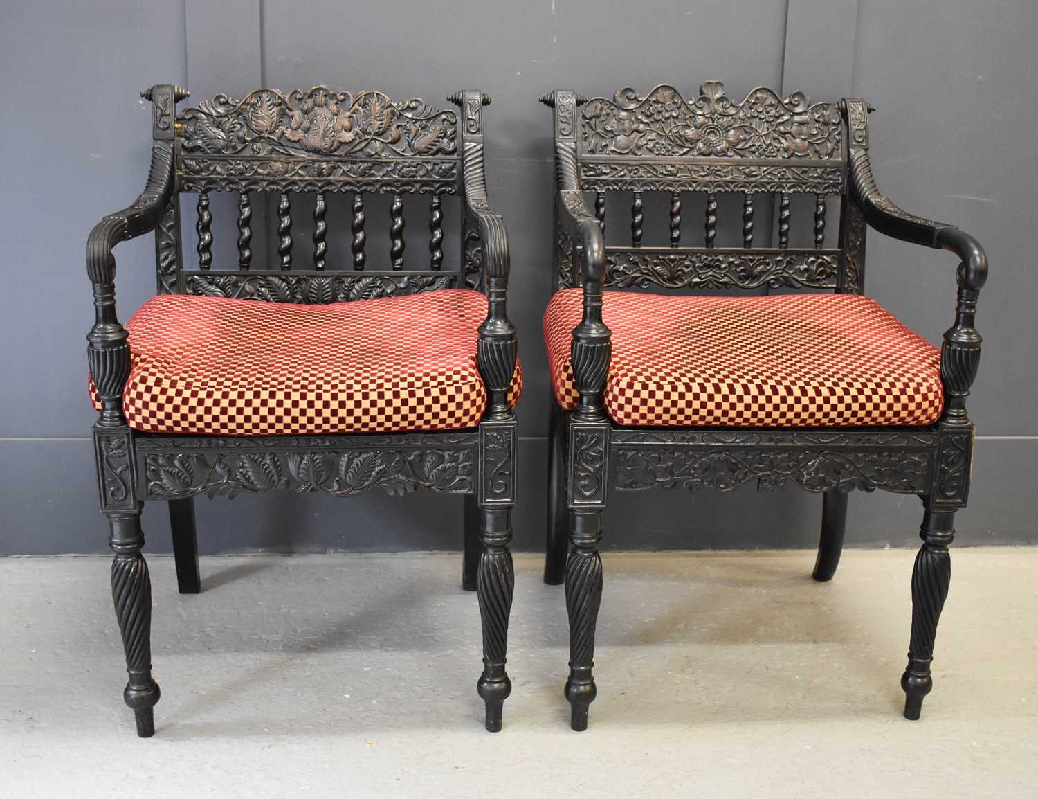 A pair of exeptional Anglo Indian ebony carved armchairs, circa 1840, Ceylonese, the shaped and