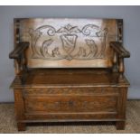 A 1930s oak Arts & Crafts period metamorphic Monks bench, with carved crest and scrolling foliate