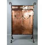 An Arts & Crafts period copper and iron fire screen, with repousee ground, and protruding rams heads