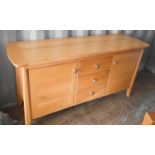 A modern beech sideboard with three short drawers flanked by two cupboard doors.