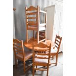 A small dining table and six ladder back chairs, with upholstered seats, 99cm diameter, 78cm high.