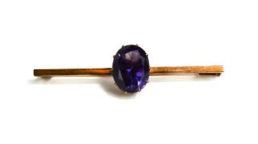 A 9ct rose gold (tested as) and amethyst set brooch / tie pin, the oval amethyst in a claw setting