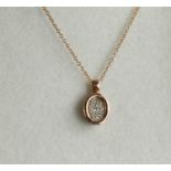 A 9ct rose gold and diamond set oval pendant and chain.