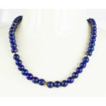 An 18ct gold and lapiz lazuli beaded necklace, with 18ct gold and paste clasp, 47g, 92cm long.