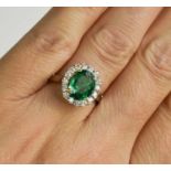 An oval emerald, platinum and diamond cluster ring, size N ½, 5.9g.