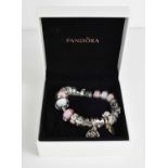 A silver Pandora charm bracelet, with nineteen various charms, in pink and white glass, in a Pandora