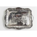 A white metal Dutch trinket dish of square form, embossed with a horse and farmer ploughing a field,