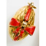 A 9ct gold pendant 'Surprise' egg, the cracked egg with red bow, opening from a hinge, to reveal a