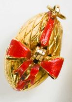 A 9ct gold pendant 'Surprise' egg, the cracked egg with red bow, opening from a hinge, to reveal a