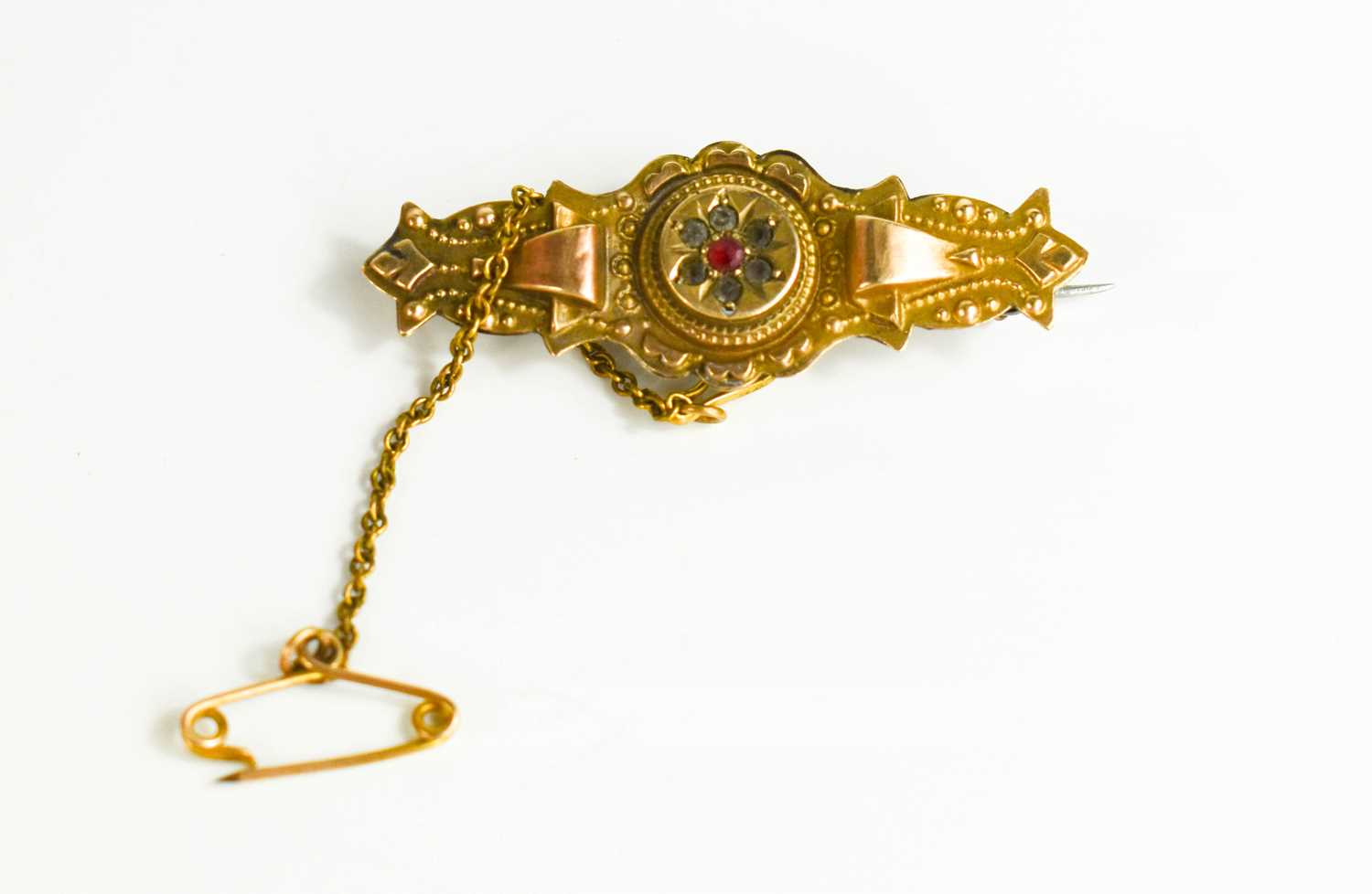 A Victorian 9ct gold brooch with central set ruby surrounded by diamonds, 2.8g