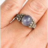 A 9ct white gold, diamond and star sapphire set ring, the central star sapphire cabochon flanked