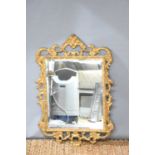 An early 20th century giltwood wall mirror decorated with foliate scrolls and scallops, 68cm by 57.