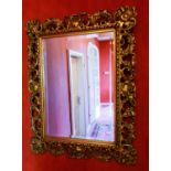 A 20th century giltwood wall mirror, with scrollwork decoration, together with a modern giltwood