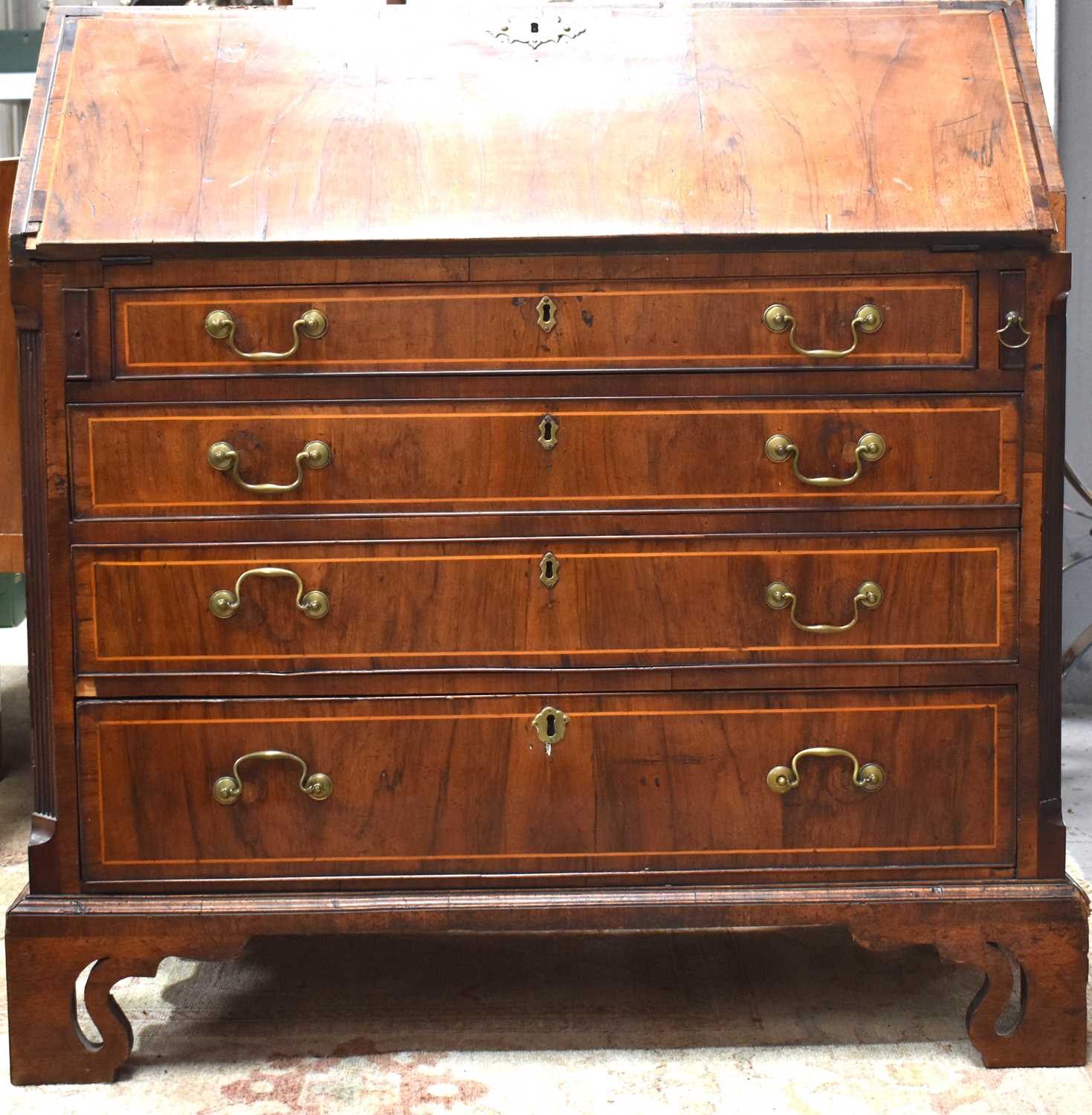 A George III walnut bureau, the fall front enclosing mahogany and satinwood crossbanding interior of