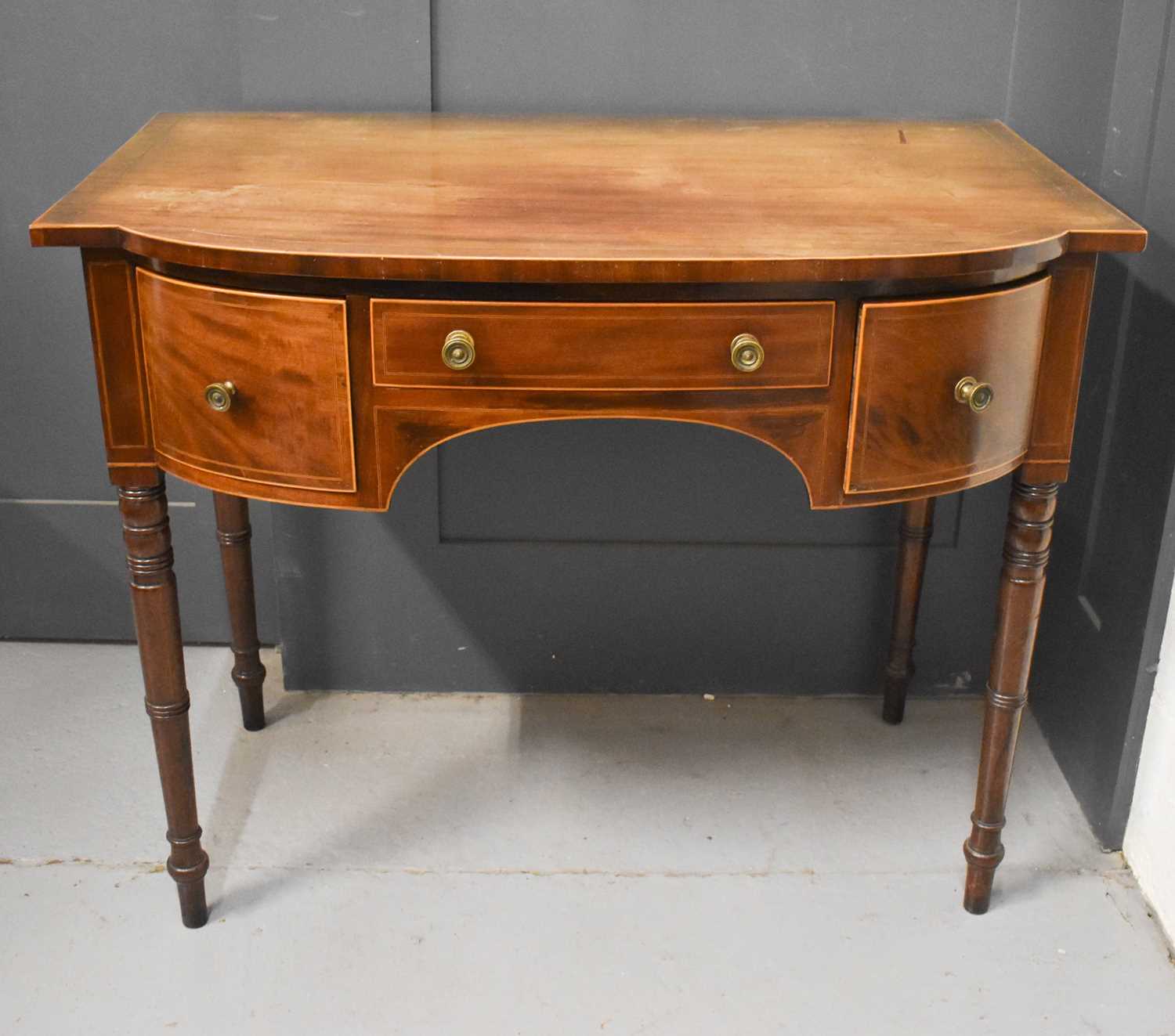 A 19th century mahogany bow front side table with three drawers set to the front and inlaid with